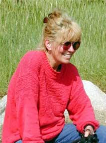 Wyndylyn, one of RedwoodESL's tutors, smiling while sitting in the grass outdoors